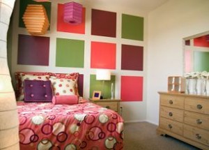 Observa cómo unos cuantos cuadros coloridos en la pared, una colcha alegre y unas lámparas de papel hacen el look de este dormitorio!